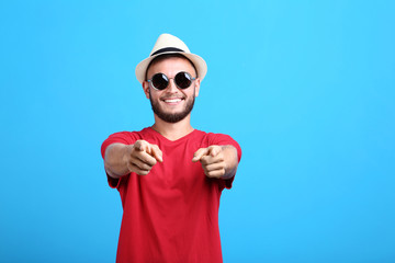 Naklejka premium Young man with sunglasses and hat on blue background