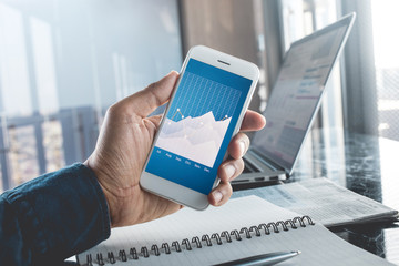 Young businessman holding smartphone with goal graph chart.Business strategic planning.study learning,blogger and freelance concepts ideas