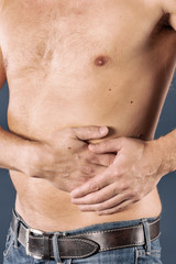 Naklejka premium Man suffering from pain in his side. Blue background. Stomach, liver pain, pancreas, kidneys
