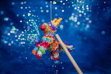 piñata para cumpleaños y navidad, colorida con luces brillantes, fondo verde y azul con manos de...