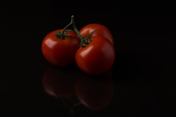 Three tomatoes on a black background