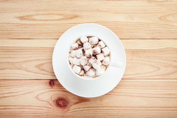 Cappuccino with marshmallows in cup on brown wooden table