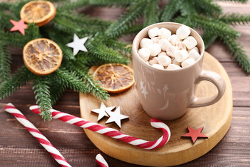Cappuccino with marshmallows, candy canes and fir tree branches on wooden table