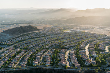 Late afternoon aerial view towards new suburban homes and streets in the sprawling Porter Ranch neighborhood of Los Angeles, California.  The Santa Susana Mountains are in the background. - obrazy, fototapety, plakaty