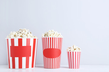 Popcorn in striped buckets on grey background