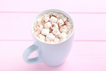 Cappuccino with marshmallows in cup on pink wooden table