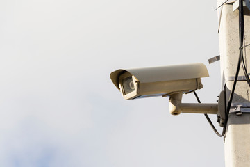 Modern compact video surveillance camera on support post in public areas on white background...