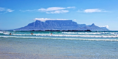 Unique Table Mountain, blue sea and surfers in Cape Town. Beautiful South Africa. People enjoy vacation in Cape Town. Amazing ocean beach. Wonderful seascape. Blouberg