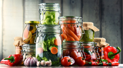 Jars with marinated food and organic raw vegetables