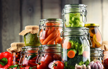 Jars with marinated food and organic raw vegetables