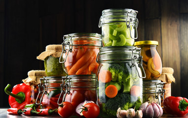 Jars with marinated food and organic raw vegetables