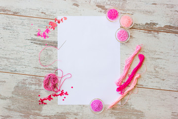 Flat lay with white sheet and pink beadson wooden background top view