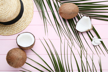 Fototapeta na wymiar Ripe coconuts with palm leafs and hat on pink wooden table