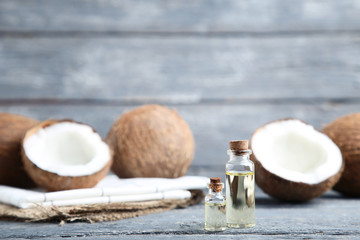 Oil in bottles with coconuts on grey wooden table