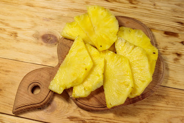 Pieces of pineapple on a cutting board on wooden table. Top view