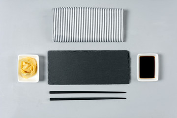 Empty black slate plate with chopstick on gray wooden background. Flat Lay. Top view. Food concept