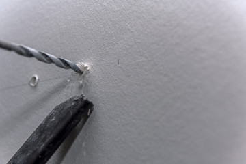 A cabinet maker drills a hole in the wall for later mounting the kitchen cabinets. Concept: craft...