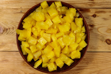 Diced pineapple in a plate on wooden table. Top view