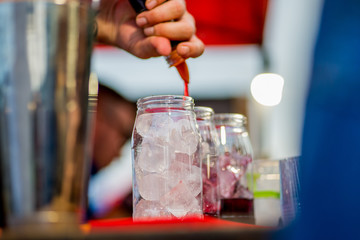barkeeper preparing a cocktail in a plastic glass outdoors. catering