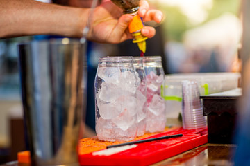 barkeeper preparing a cocktail in a plastic glass outdoors. catering