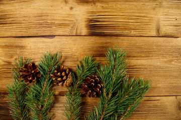 Christmas composition with fir tree branches and cones on wooden background. Top view, copy space