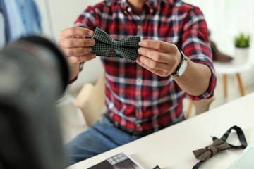 Fashion blogger with bow tie recording video on camera at home