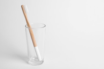 Glass with bamboo toothbrush on white background. Space for text