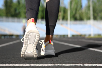Fototapeta na wymiar Sporty woman running at stadium on sunny morning, focus on legs