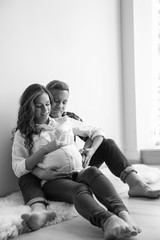 Pregnant woman with her husband indoors, black and white effect