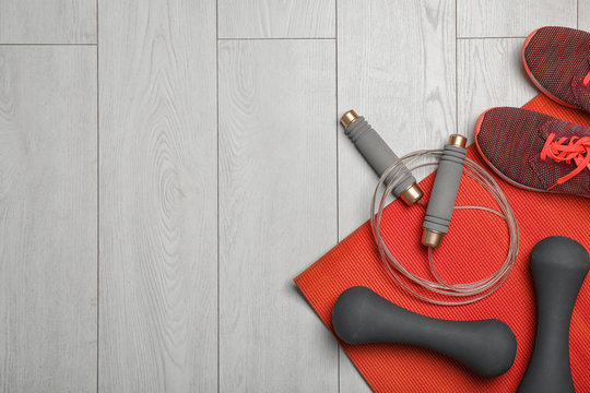 Flat lay composition with jump rope, gym equipment and space for text on wooden background