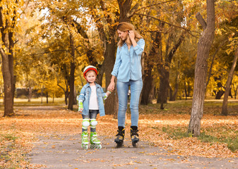 Fototapeta premium Mother and her daughter roller skating in autumn park