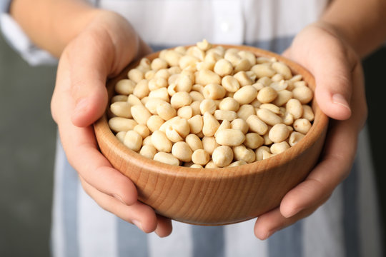 Woman holding bowl with shelled peanuts, closeup