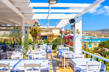 Fototapeta premium Terrace with tables in traditional Greek tavern decorated with flowers in Ammopi village on Karpathos island, Greece