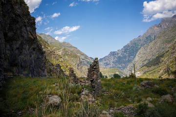 Fototapeta na wymiar Mountain green valley with a deep gorge, high mountains and hills covered with grass, rocky gorge with a mountain river at the bottom. Landscapes of Georgia, Georgian military road.