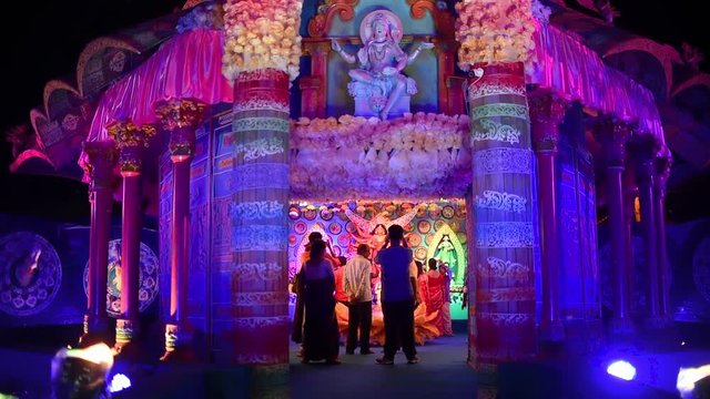 Indian Gods and Goddess in colorful temples or pandals in Hindu festival Durga Puja, people visiting inside to pray at night
