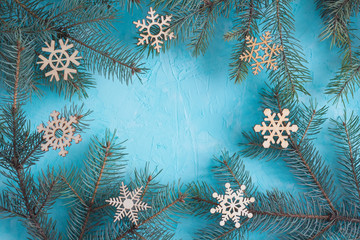 Fototapeta na wymiar Christmas frame top view. Fir branches and wooden snowflakes on the blue background