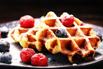 waffles with fresh blueberries, sugar and raspberries.
