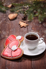 A Cup of coffee and ginger cookies on a wooden background decorated with fir branches and toys for the New year or Christmas. Valentine's day.Cookies in the shape of a heart.