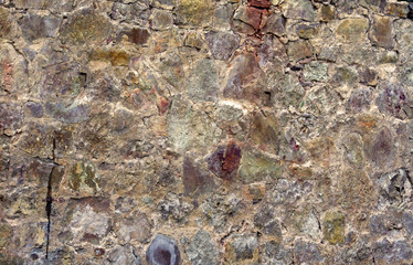a piece of a flat stone wall, an old cracked surface consists of stones and rocks of various shades...