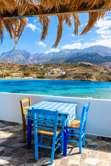 Terrace with table in traditional Greek tavern in Lefkos port on Karpathos island, Greece - obrazy, fototapety, plakaty