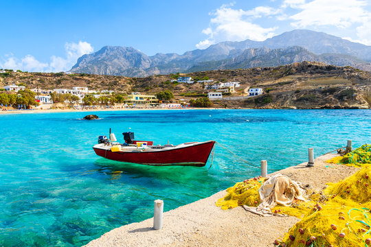 Boat on sea in Lefkos port with fishing nets on shore, Karpathos island, Greece