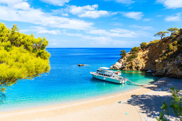 Tourist boat on beautiful Apella beach with azure calm sea water, Karpathos island, Greece