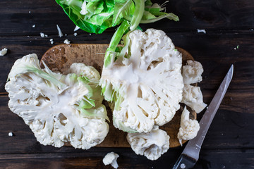 Cauliflower on the wooden board with knife. Still life of food. Process of cooking. Vegetarian concept. Cooking concept. Vegan food. Cabbage. Organic food.
