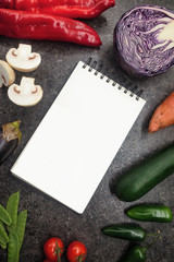 Fresh juicy vegetables border, blank white notepad with copy space, top view. Mockup for healthy dish recipe.  Dark table