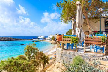 Taverna terrace on beautiful beach in Lefkos village on coast of Karpathos island, Greece - obrazy, fototapety, plakaty