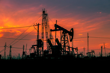Functioning oil rigs at beautiful sunset, blurred background
