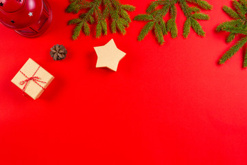 Christmas composition. Fir tree branches, pine cones and present gift boxes on red background