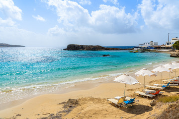 Sunbeds on beautiful beach in Lefkos village on coast of Karpathos island, Greece.