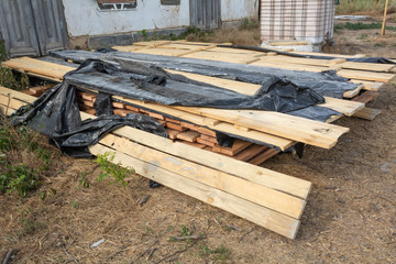 Obraz premium A stack of pine boards soaked in an antiseptic solution is dried at the construction site. Building materials for the construction of a frame house.