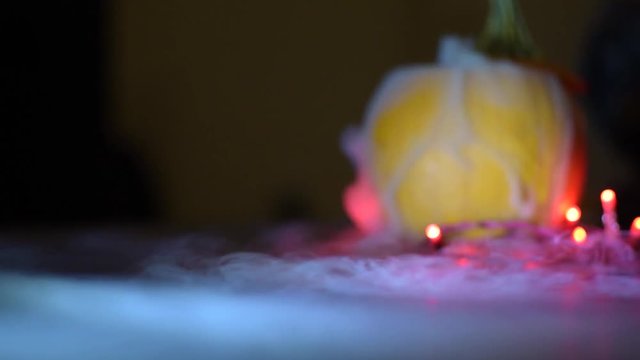 dry ice mist fog flowing from a pumpkin onto a flat surface, lights around the pumpkin